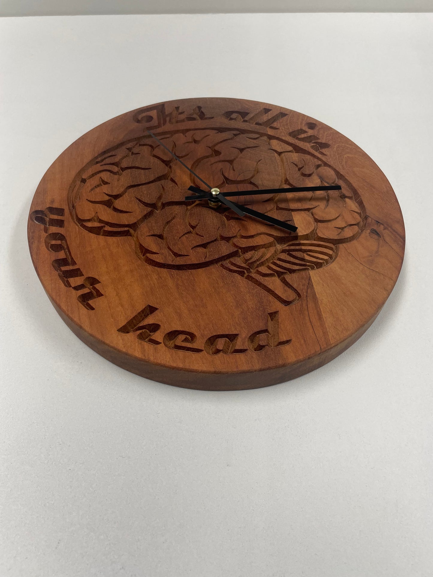 Carved mahogany wall clock with anatomical brain design and "It's all in your head" text
