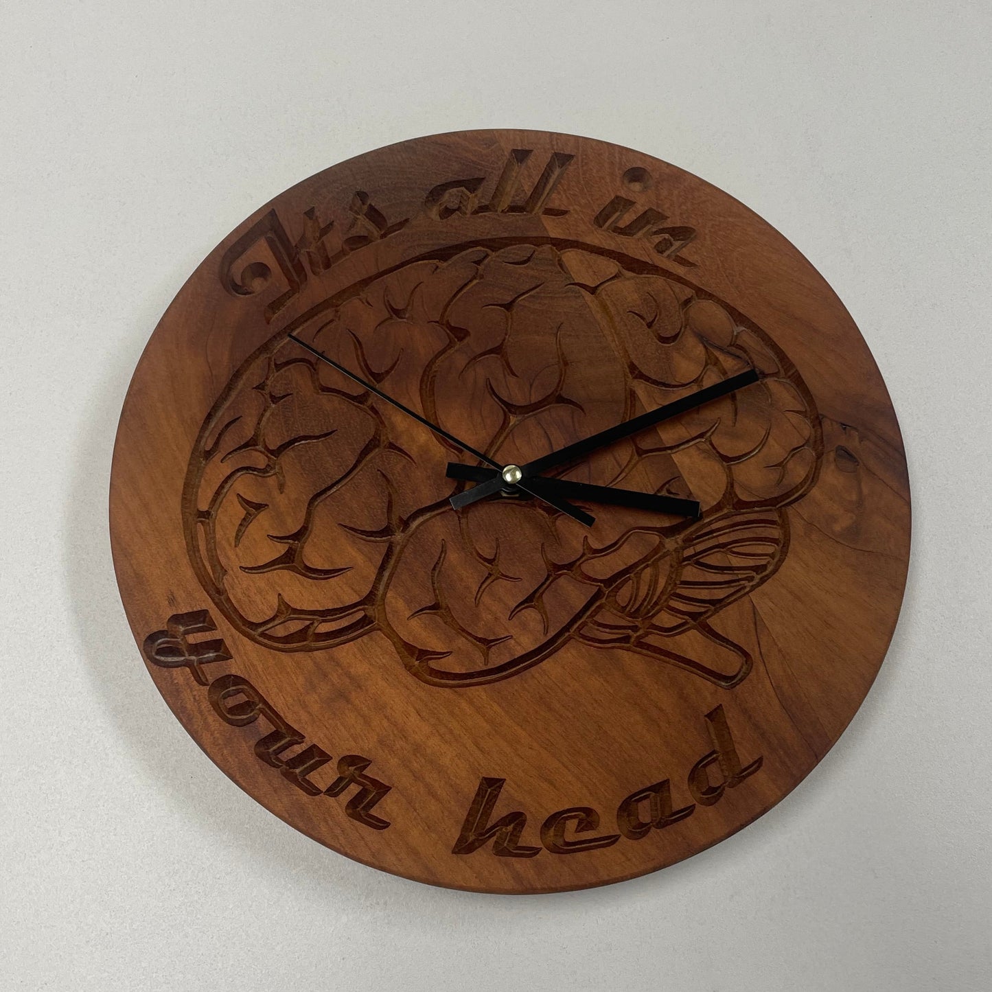 Carved mahogany wall clock with anatomical brain design and "It's all in your head" text