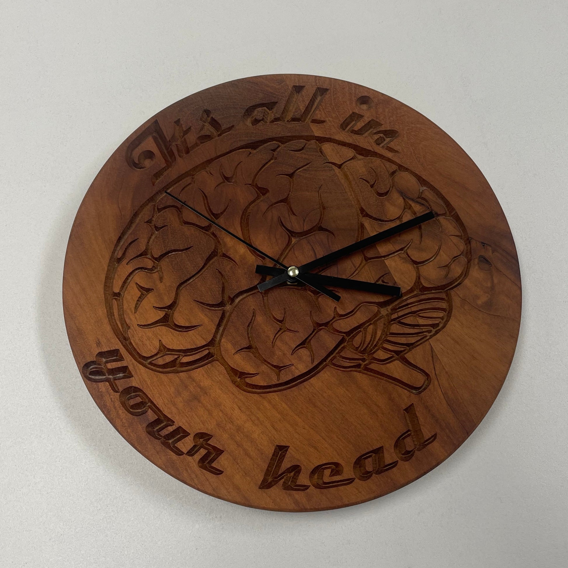 Carved mahogany wall clock with anatomical brain design and "It's all in your head" text