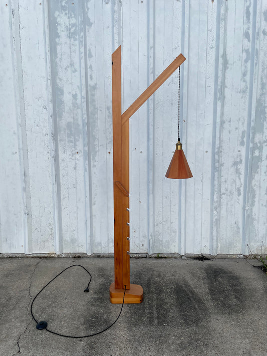 adjustable height Wooden lamp with a cone-shaped wwoden shade on a concrete surface with a cloth cord and footswitch 